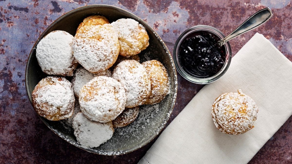 Aebleskiver mit Marmelade auf violettem Untergrund.