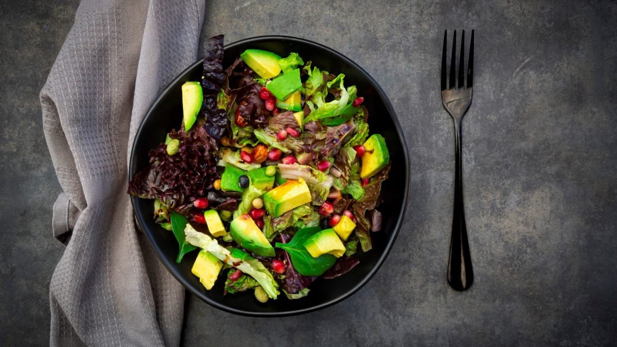 Avocado-Salat mit Granatapfel auf Teller angerichtet.
