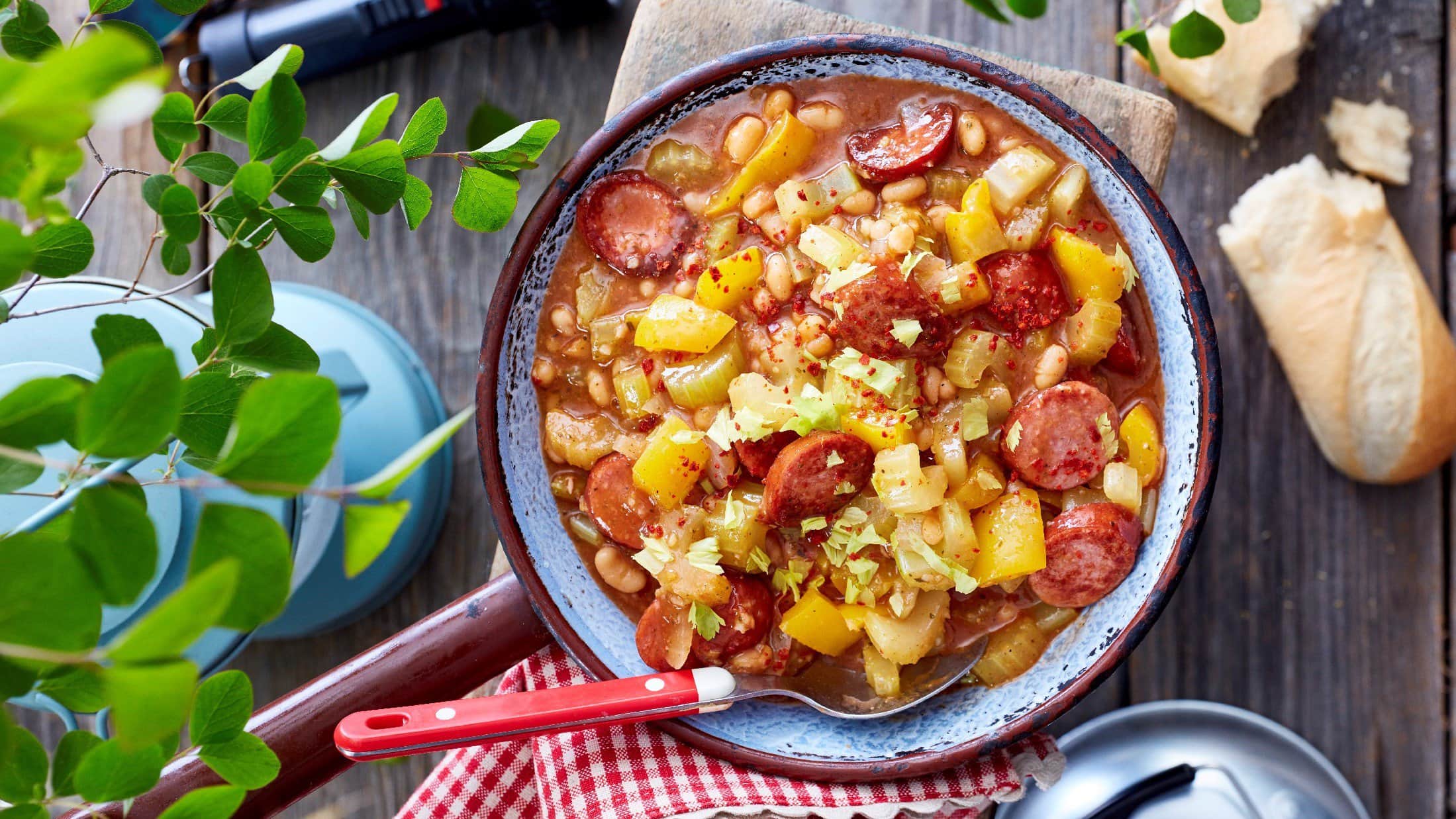 Baked Beans Pfanne von oben mit Petersilie Tuch und Baguette im Hintergrund