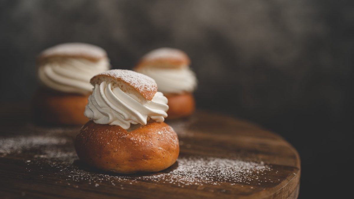 Drei Schwedische Semlor auf Holzbrett und dunklem Hintergrund