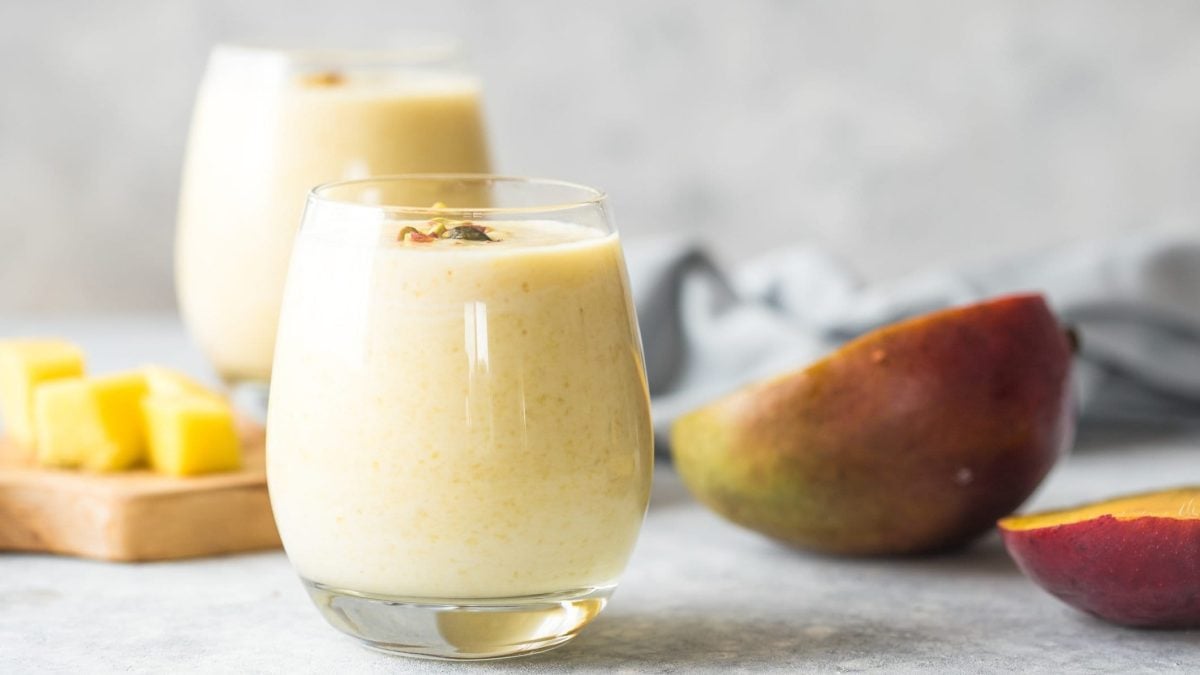 Ein Glas Kefir-Smoothie im Vordergrund, eines im Hintergrund. Mango zusätzlich als Deko.
