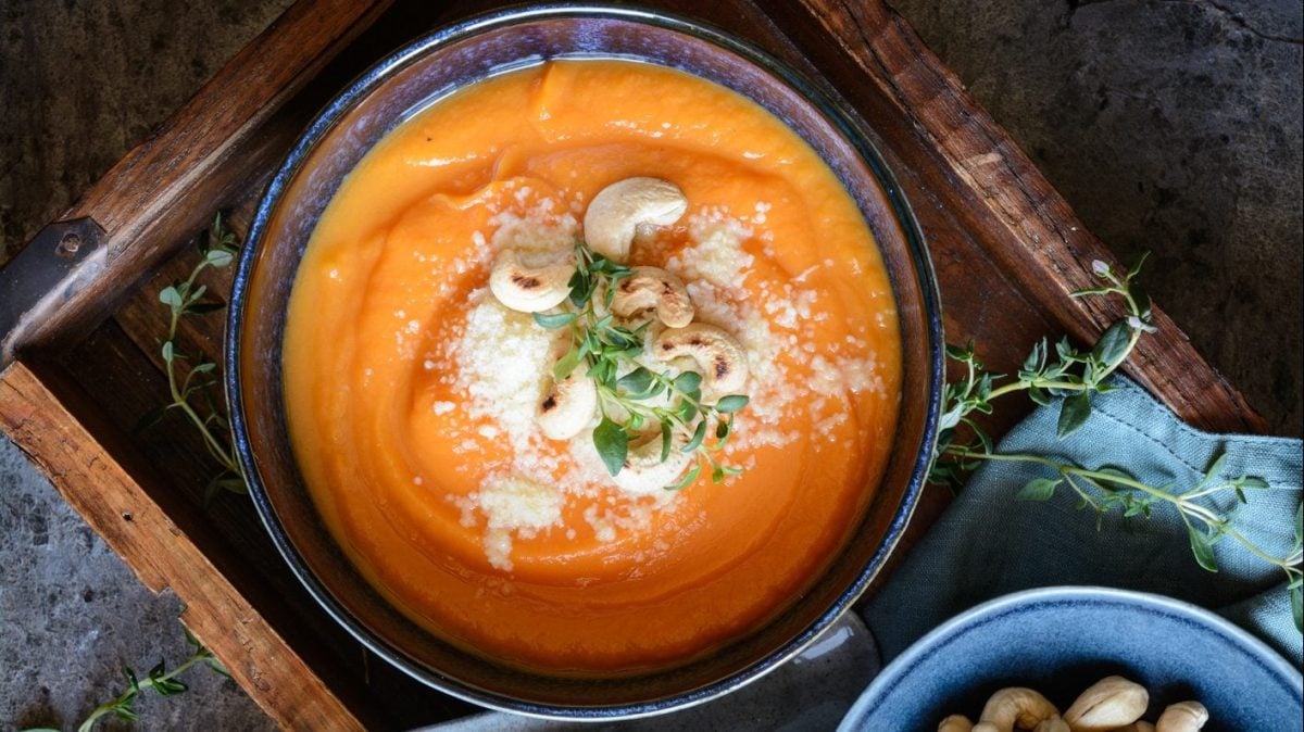 Unsere Süßkartoffelsuppe mit Pecorino und Cashews auf einem Tablett angerichtet.