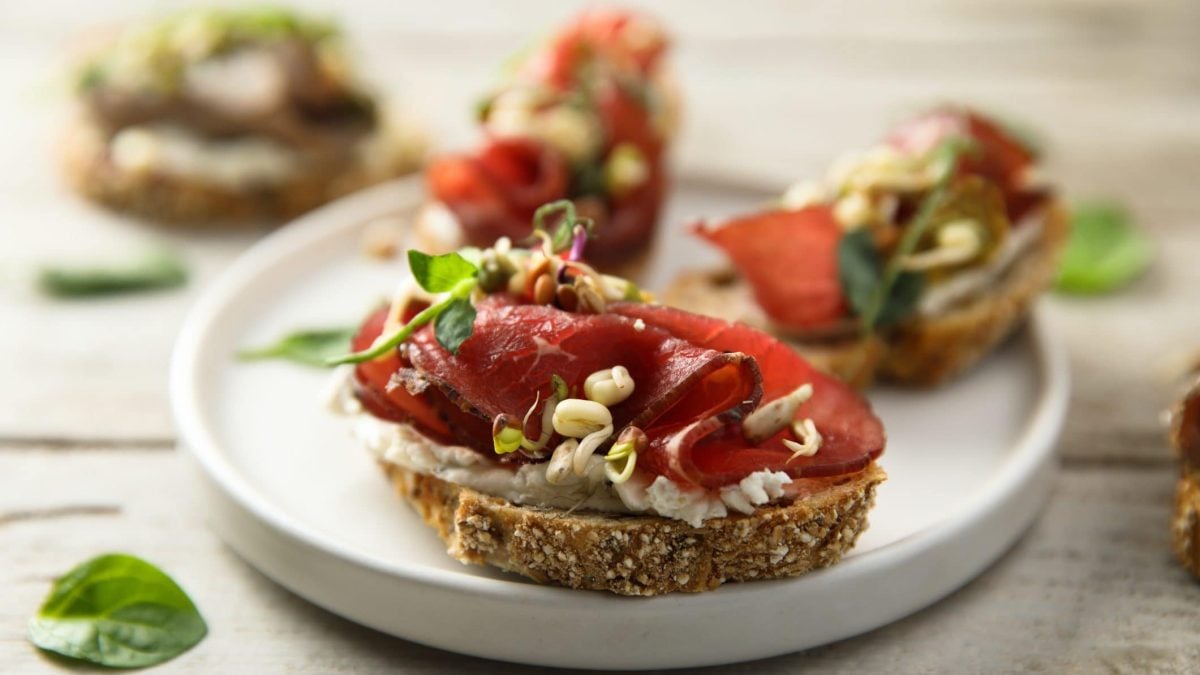 Das Carpaccio-Bruschetta liegt auf einem runden weißen Teller.