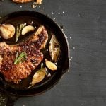pfanne mit fleisch und gewürzen von oben auf schwarzem tisch