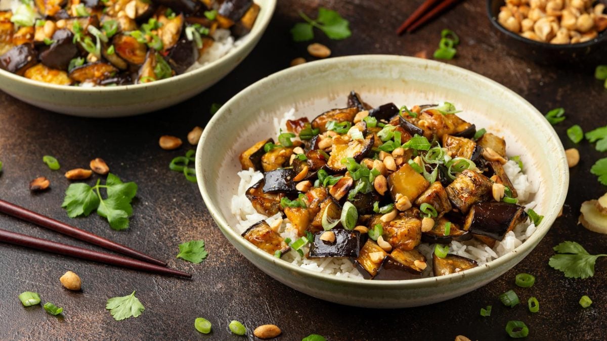Gebratene Aubergine mit Erdnusssauce und Reis, Frühlingszwiebeln und Erdnüssen.