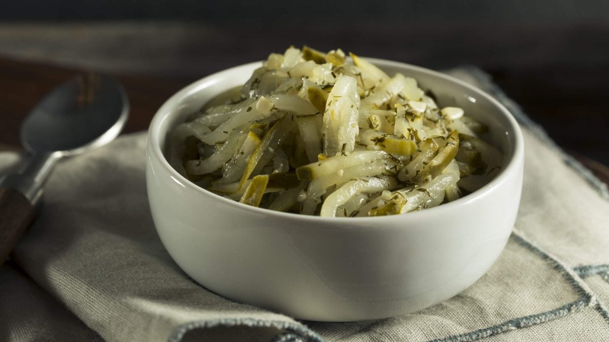 Eine Schale Dill-Gurken-Relish auf einem Geschirrtuch, daneben ein Löffel.