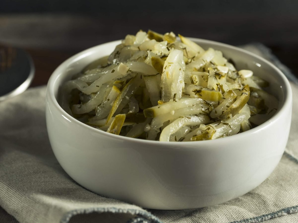Eine Schale Dill-Gurken-Relish auf einem Geschirrtuch, daneben ein Löffel.