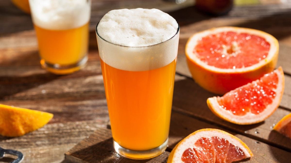 Zwei IPA Paloma Bier-Cocktail mit Tequila aus Holzbrett. Ebenfalls aufgeschnittene Grapefruit- und Zitronenspalten. Frontalansicht.