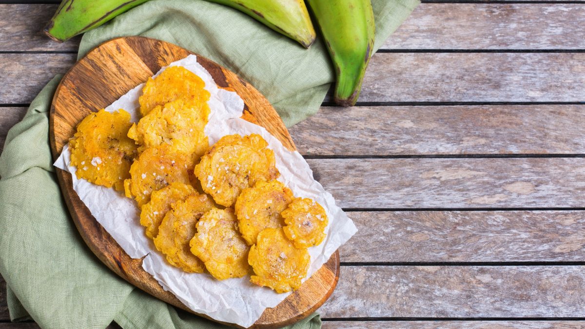 Kochbananen-Chips, frittiert auf einem Brett mit Backpapier, auf einem Holztisch