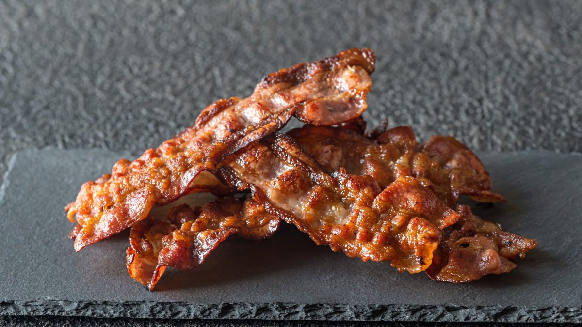 Maple Bacon Scheiben auf Schieferplatte auf grauem Untergrund. Frontalaufnahme.