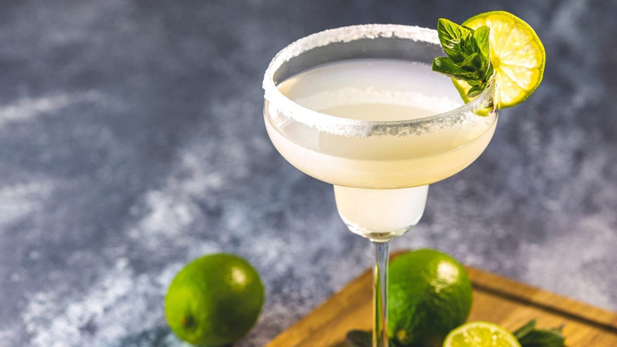 Ein Glas Margarita mit einer Limettenscheibe und Minze dekoriert.