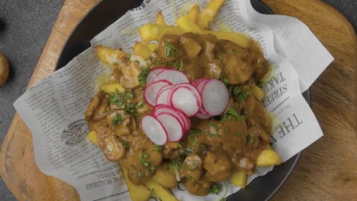 Unsere Poutine, angerichtet auf Zeitungspapier in einem schwarzen Teller.