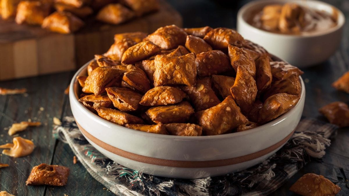 Eine Schüssel Pretzel Bites, dahinter unscharf weitere Pretzel Bites auf einem Holzbrett.