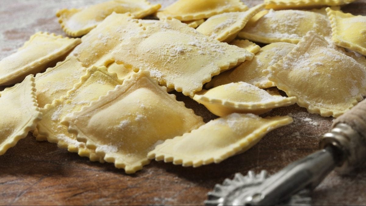 Auf einer Holzplatte lieben gefüllze Nudeln, die nach einem Ravioli-Grundteig-Rezept zubereitet wurden.