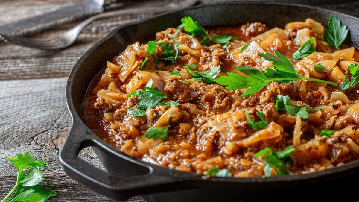 Auf einem Holztisch steht eine Weißkohl-Hackfleisch-Pfanne