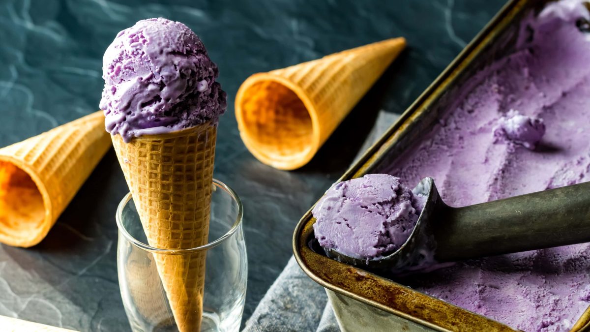 Ube-Eiscreme mit Ausstecher und Waffel auf dunkelgrünem Untergrund