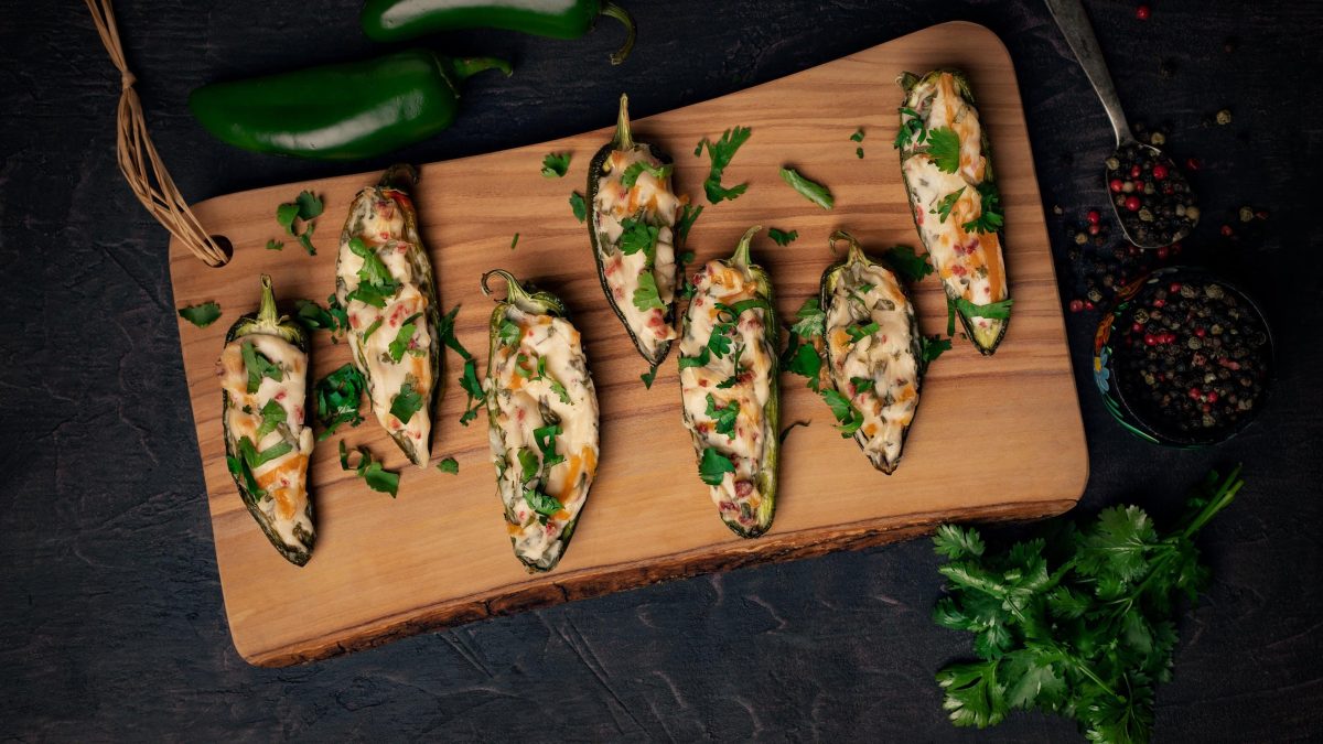 Vegane Jalapeño Poppers auf einem Holzbrett in der Draufsicht.