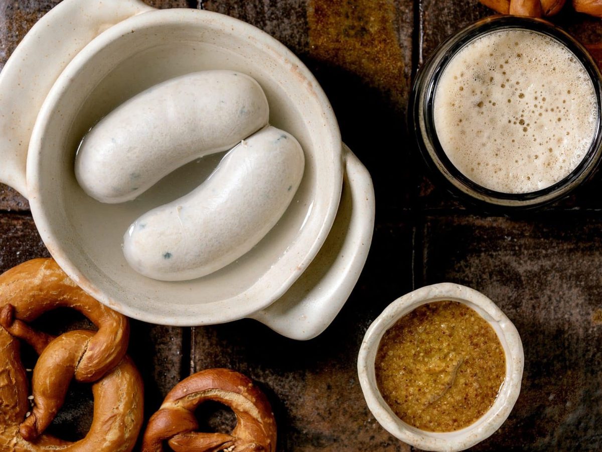 Aus der Vogelperspektive: Ein bayerisches Weißwurstfrühstück: Es gib Brezen, süßen Senf, Weißwurst und ein Bier.