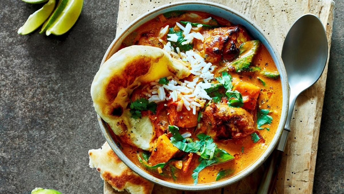 Eine Portion Butter Chicken mit Reis serviert in einer Schüssel.