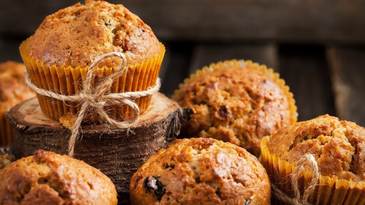 Auf dem Bild sind mehrere Möhren-Muffins zu sehen. Sie sind mit Nüssen und Schokotröpchen im Teig gebacken.