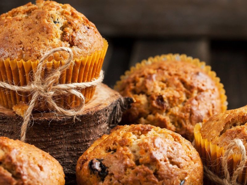 Auf dem Bild sind mehrere Möhren-Muffins zu sehen. Sie sind mit Nüssen und Schokotröpchen im Teig gebacken.