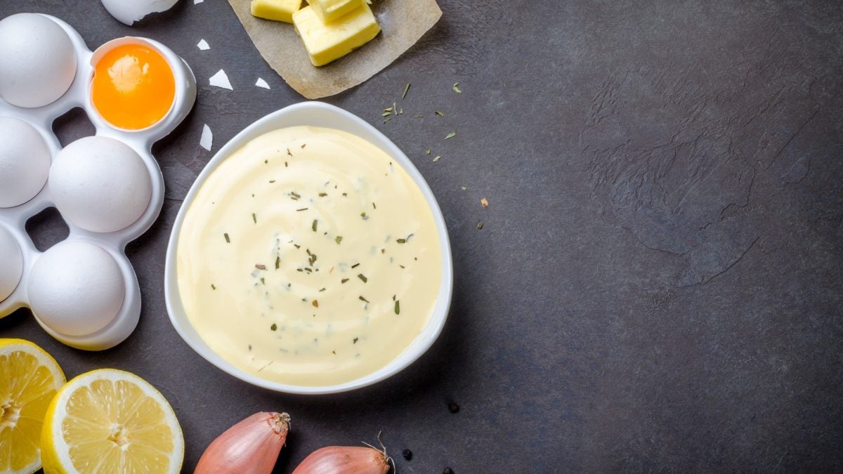 Sauce béarnaise mit den zugehörigen Zutaten auf dunklem Untergrund.