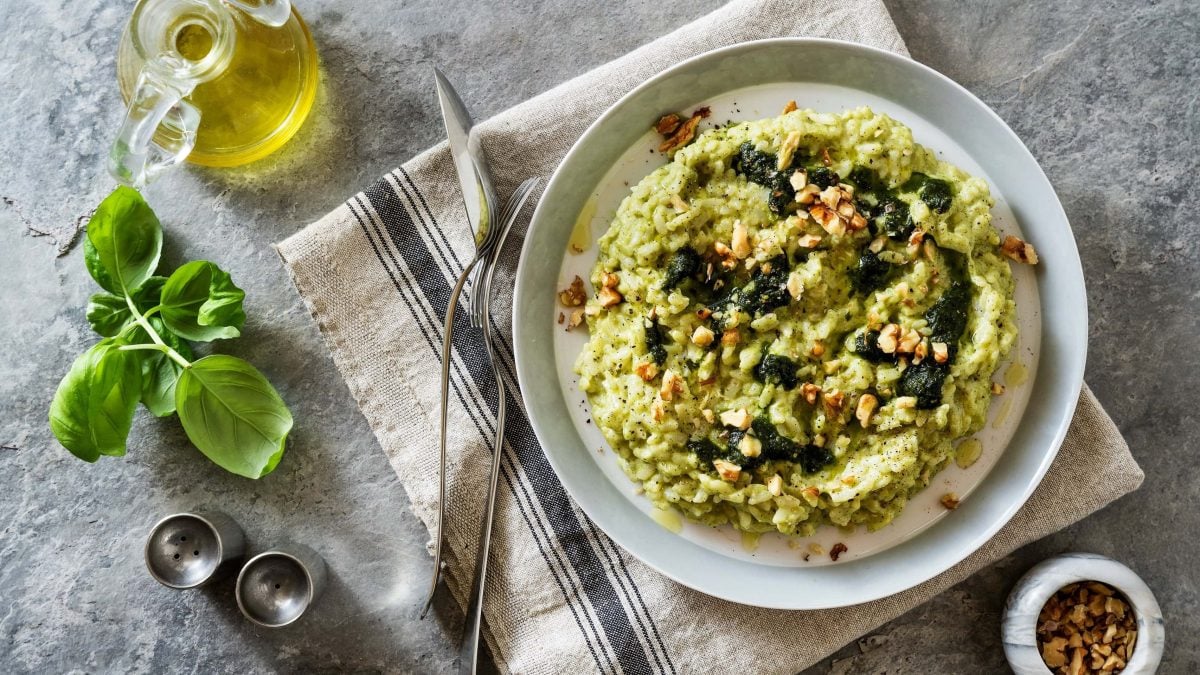 Ein Teller Bärlauch-Risotto mit Walnüssen in der Draufsicht, daneben Zutaten wie Weißwein und Nüsse.