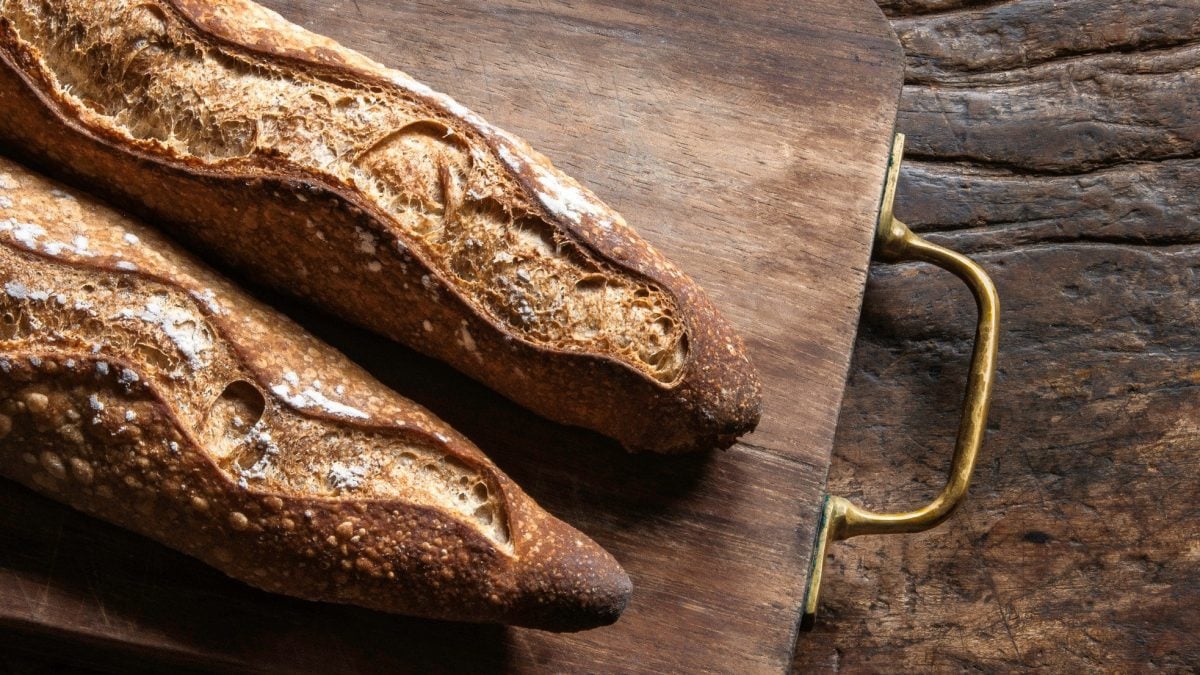 Zwei original Französische Baguettes auf Holzbrett und Holztisch. Aufnahme aus der Vogelperspektive.