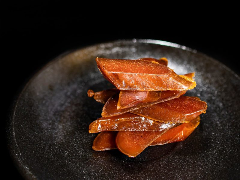 Bottarga auf einem schwarzem Teller und schwarzem Hintergrund