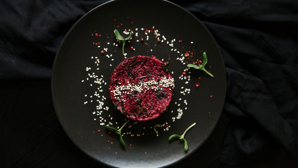 Rote Bete Salat von oben auf schwarzem teller und schwarzem Untergrund.