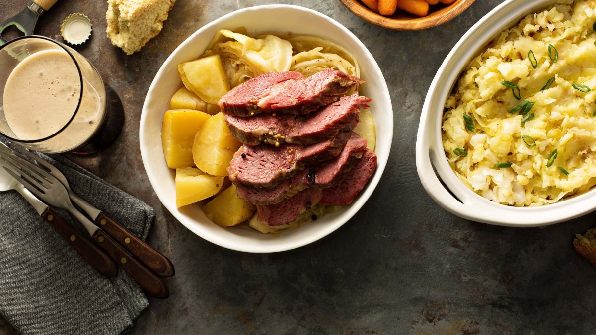 Schale mit Corned Beef und Cabbage auf schwarzem Tisch.