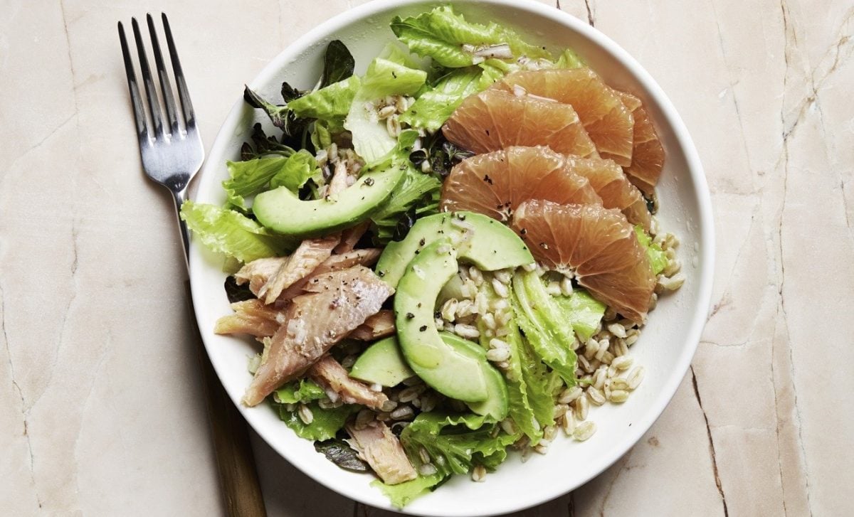Saftiger Forellen-Salat mit Grapefruit, Avocado, Graupen, Blattsalat und frischem Zitronendressing in einer weißen Schale auf hellem Holztisch, von oben fotografiert.