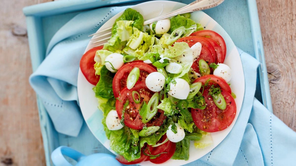 Unser grüner Salat mit Caprese fein angerichtet in einer Salatschüssel.