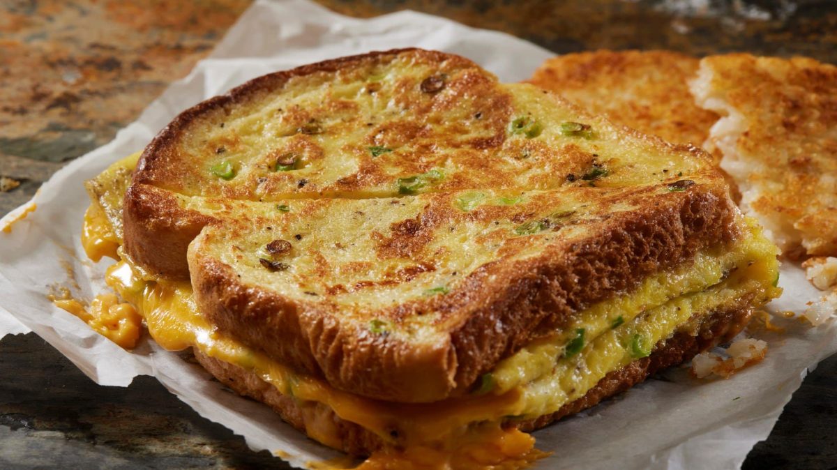 Seitliche Aufnahme des Sandwichs aus dem Käse läuft auf Pergamentpapier.