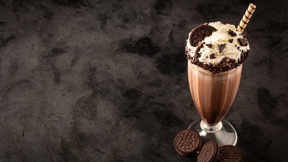 Oreo Milkshake in einem Glas. Das Ganze auf einem dunklen Untergrund.