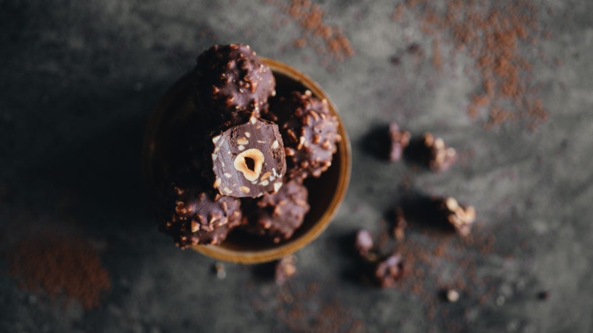 Selbstgemachte Rocher in einer Holzschale auf dunklem Untergrund mit Kakaopulver.