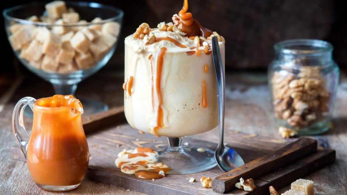Salted Caramel Milkshake auf einem Holzbrett. Daneben verschiedene Zutaten.
