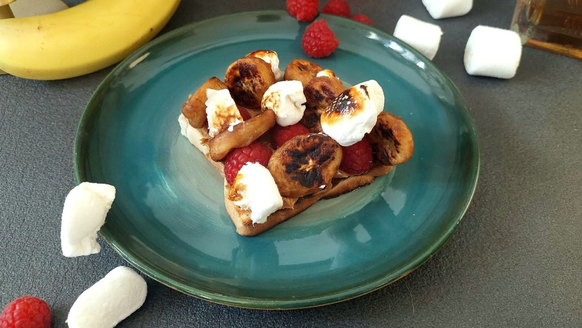 Elvis Sandwich auf blauem teller und dunklem Untergrund. Himbeeren und Marshmallows drum herum verteilt.