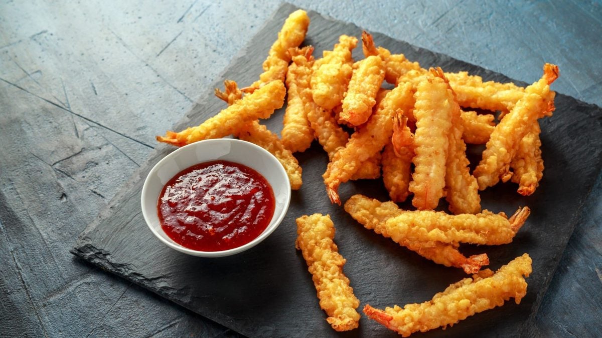 Shrimp Tempura auf einer Schiefernplatte. Daneben eine schale mit süß-saurer Sauce.