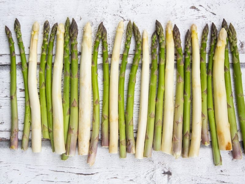 Weißer und grüner Spargel auf einem Brett aufgereiht