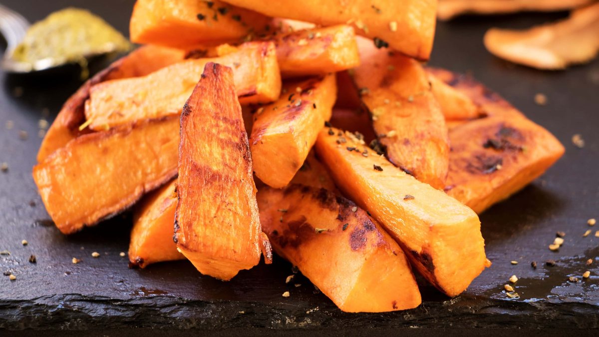 Süße Sweet Potato Wedges auf einer schwarzen Schieferplatte.