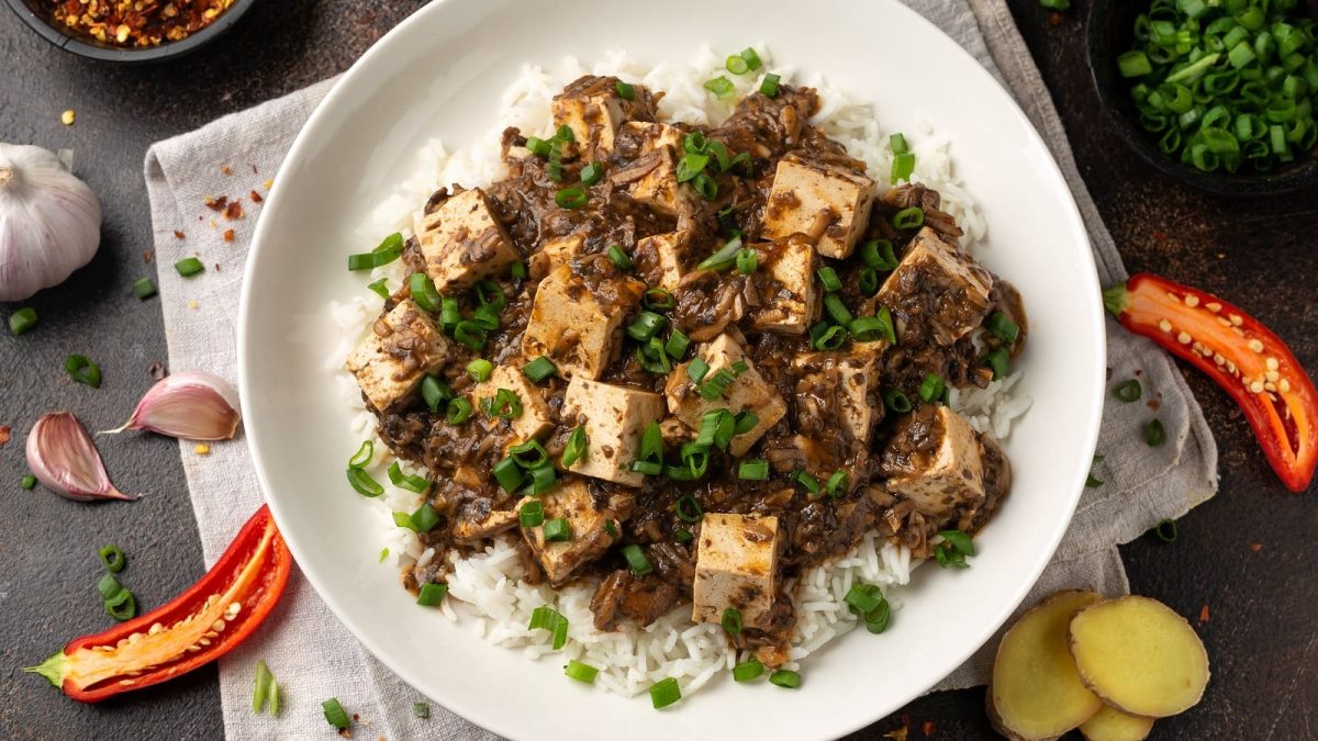 Ein Teller mit veganem Mapo-Tofu neben frischer Chili und Ingwer