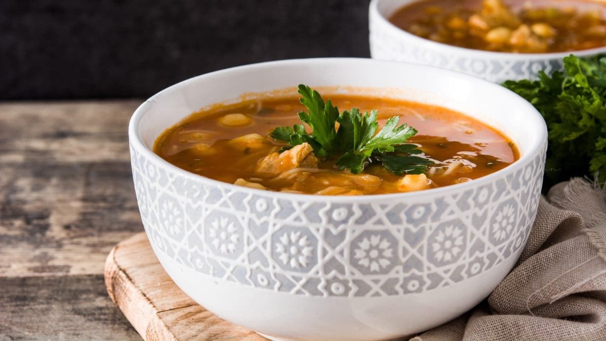 Zwei Schüsseln mit veganer marokkanischer Harira-Suppe, eine rote Suppe mit Kichererbsen und Tomaten, mit Petersilie garniert.