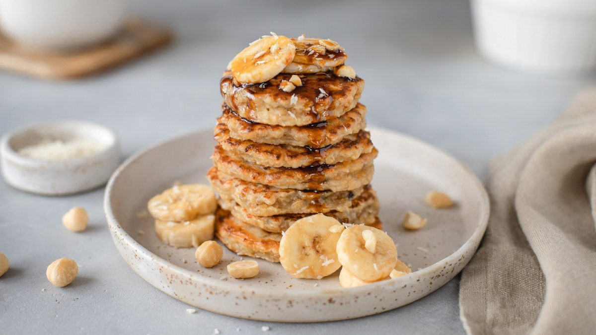 ein Stapel vegane Pancakes mit Haferflocken und Bananenscheiben.