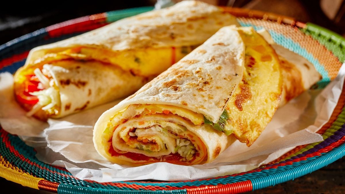 Zwei vegane Rolex, gerollte Teigfladen gefüllt mit Gemüse und Omelette, in einem bunten Korb.