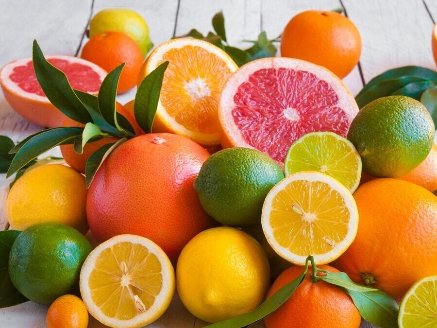 Auf einem weißen Untergund aus Holz liegen viele Zitrusfrüchte. Diese sind wertvolle Vitamin-C-Lieferanten.