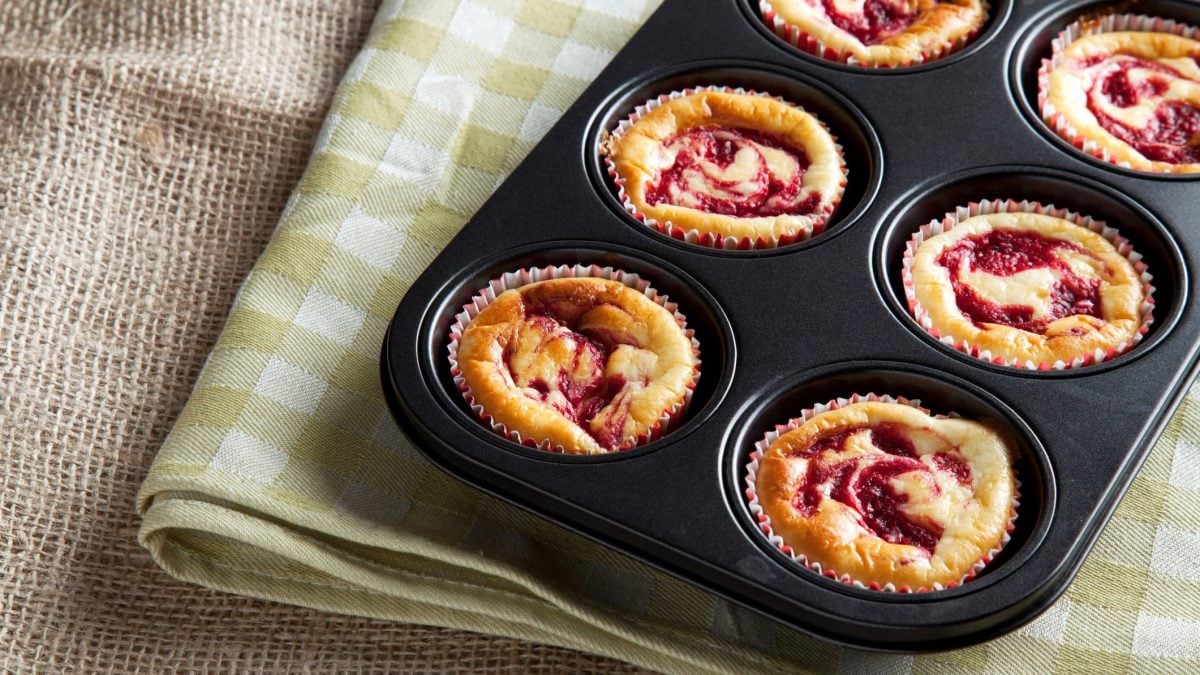 Eine Muffin-Backform gefüllt mit Himbeer-Cheesecake-Muffins.