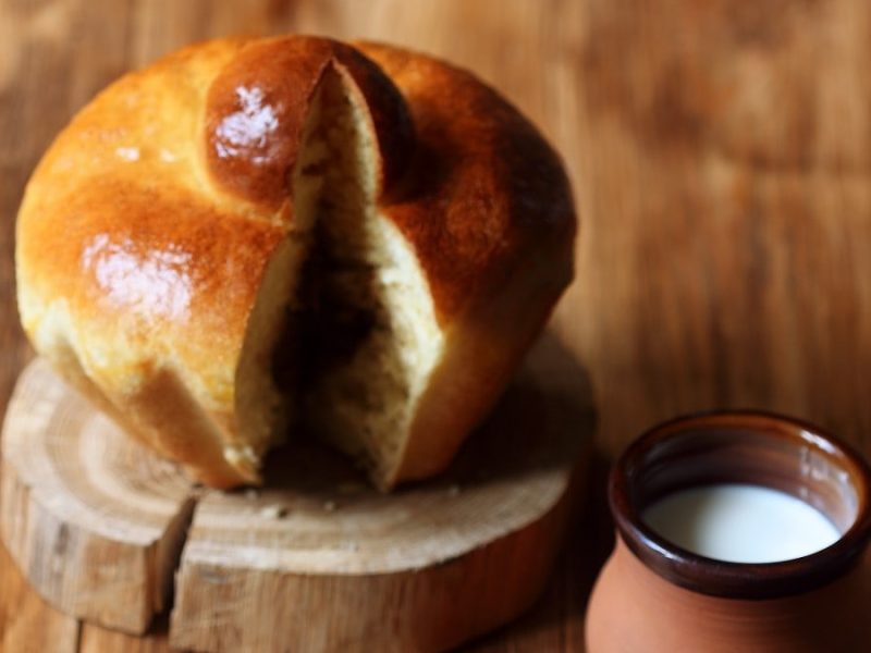 Saftige französische Brioche-Broetchen, angeschnitten auf einem kleinen Holzbrett mit etwas frischem Schmand dazu gereicht.