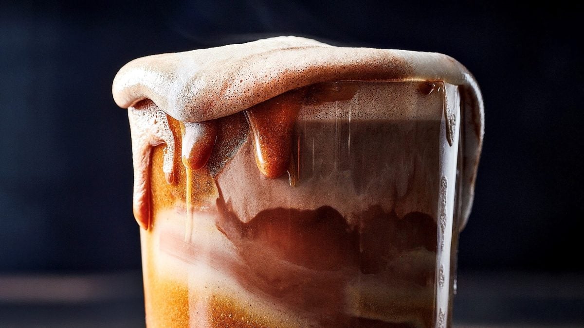 Ein Glas mit Cookiebutter-cappuccino, der über den Rand hinausläuft.