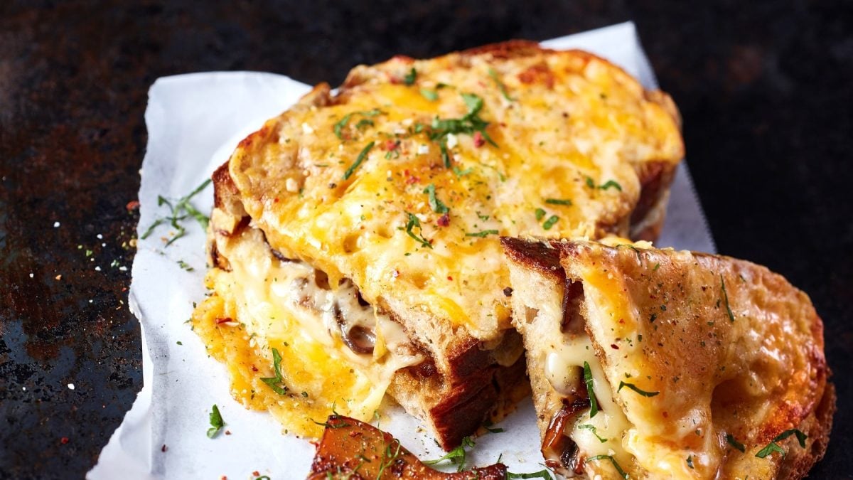 Zwei Grilled Veggie Sandwiches auf einem Stück Pergament auf dunklem Untergrund.